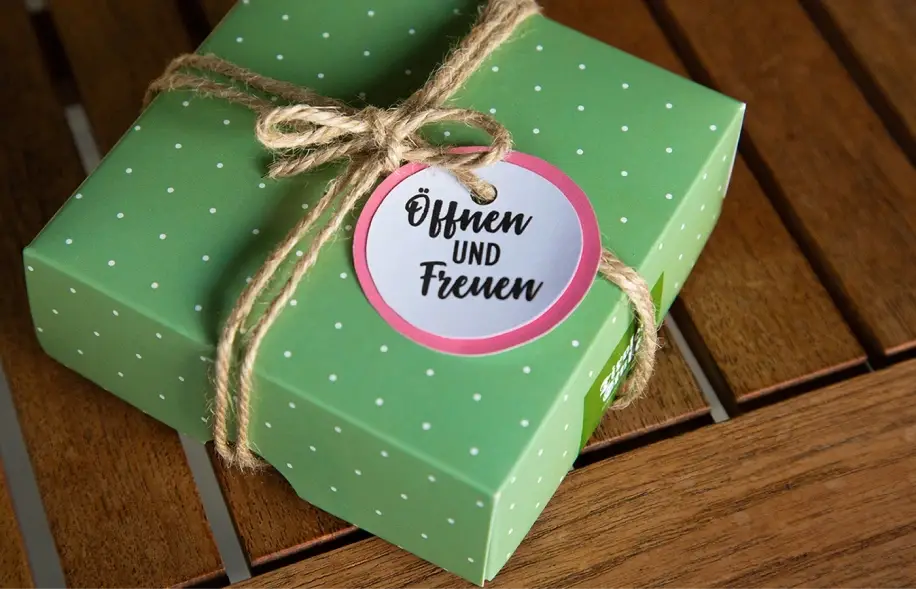 Geschenksverpackung des Tirolerstuben Gutschein. Grünes Paket mit Schleife.
